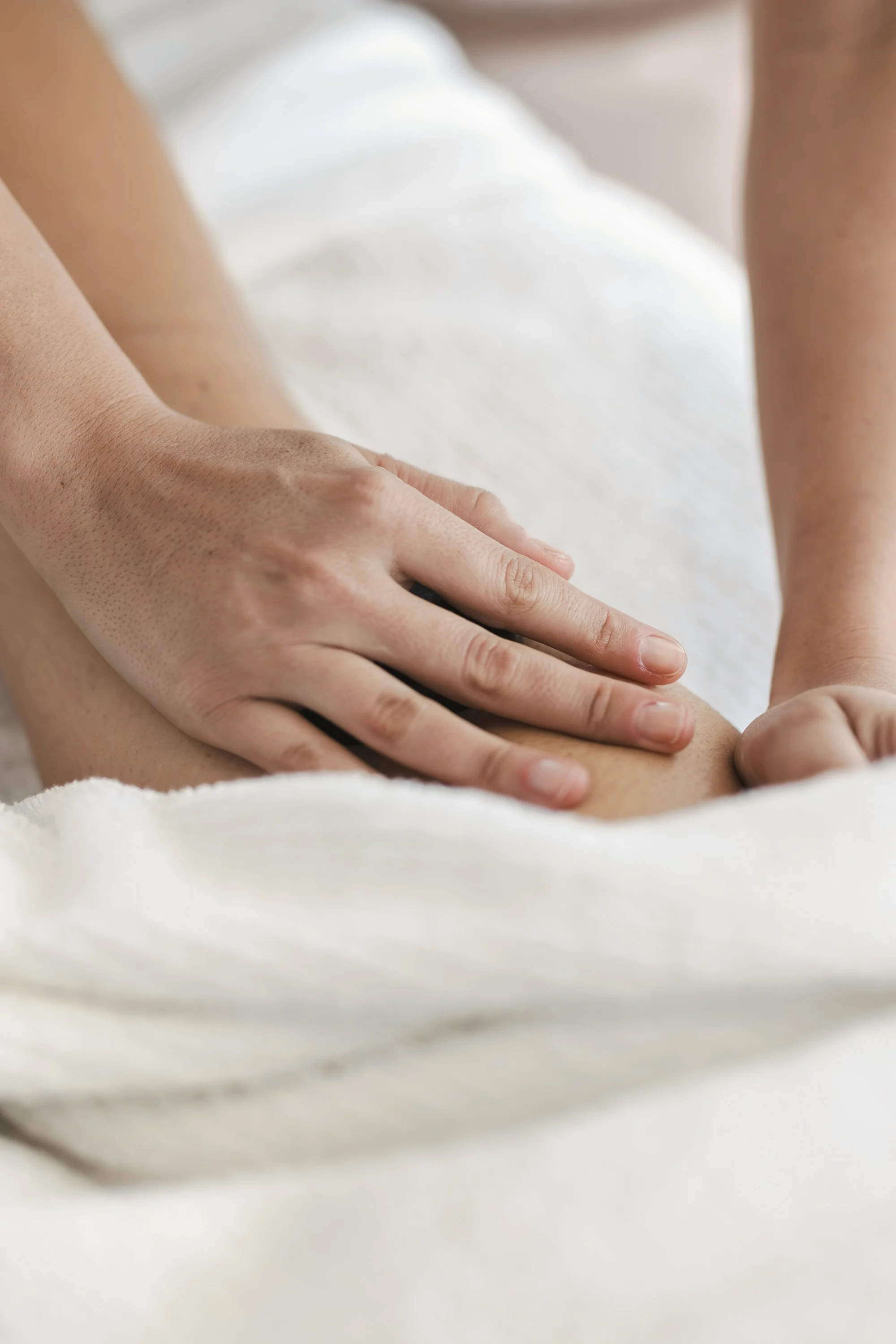 Ruke terapeuta masiraju leđa pacijenta pokrivenog bijelim ručnikom.